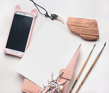 white Android smartphone beside paintbrush and conch shell thumbnail