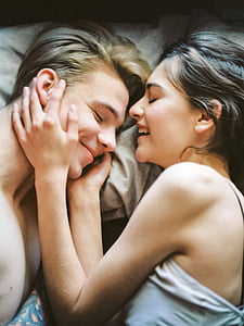 man and woman in white top laying on bed thumbnail