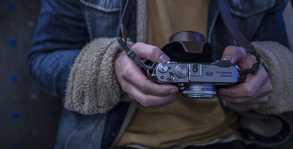 person in blue jacket holding gray camera thumbnail