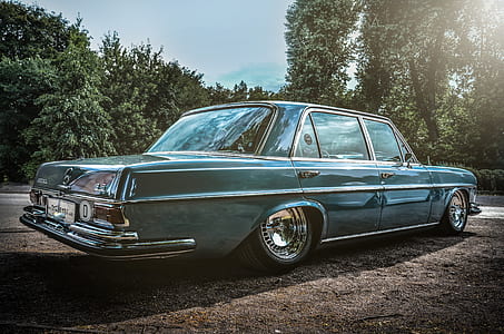 classic teal sedan parked near trees thumbnail