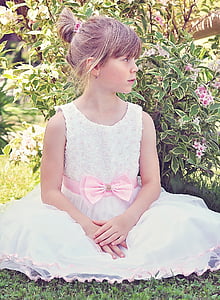 girl in white sleeveless gown sitting beside the flowers thumbnail