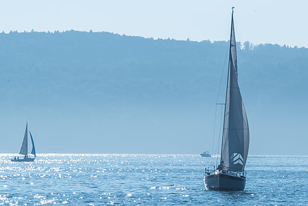 white sailboat on body of water near mountain at daytime thumbnail