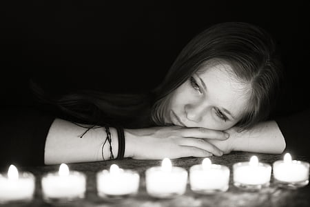 grayscale photo of woman laying looking tealight candles thumbnail
