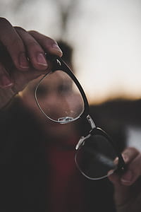 selective focus photography of man holding eyeglasses thumbnail
