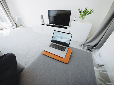 MacBook Pro on gray sectional sofa in white room thumbnail