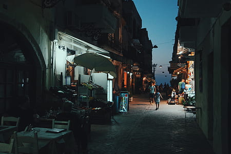 low-light photo of people walking on street between buildings thumbnail