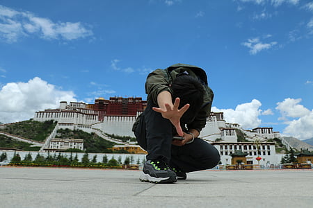 person wearing black hoodie near white concrete building thumbnail
