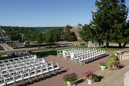 pile of white folding chairs in front of gray concrete stage under blue sky thumbnail
