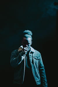 Man Wearing Denim Jacket Singing on Stage thumbnail