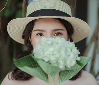 Woman Wearing White Hat Holding Flowers thumbnail