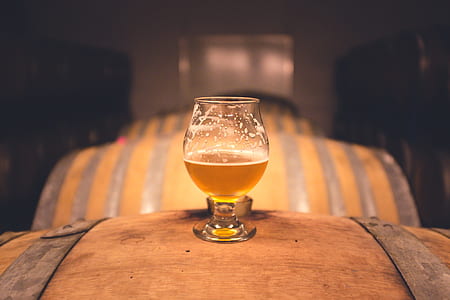 shallow focus photography of clear goblet glass on top of beer barrel thumbnail