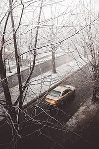 grey sedan travelling on road while snowing during daytime thumbnail