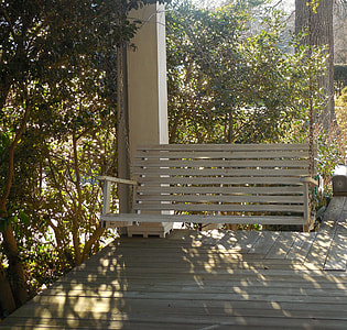 white swing bench surrounded by plants thumbnail