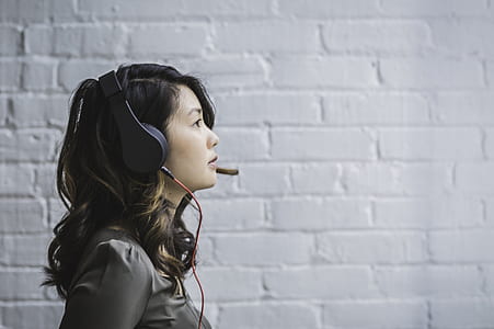 woman wearing black headphones facing on right beside white wall thumbnail