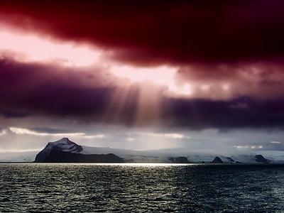 body of water near white and black island under green, gray, and purple sky thumbnail