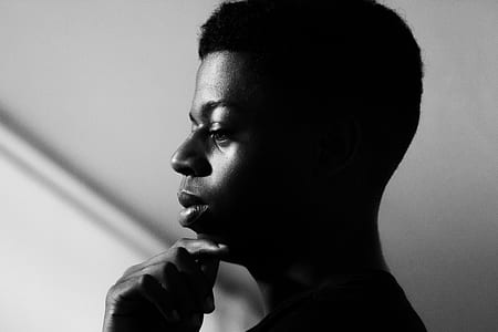 greyscale photography of man's face while putting his hand on his chin thumbnail