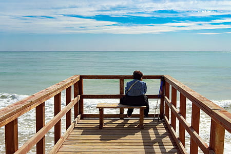 girl sitting on bench looking at ocean thumbnail