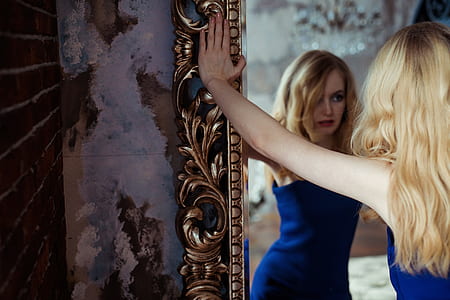 woman wearing blue sleeveless shirt holding the frame of a mirror thumbnail