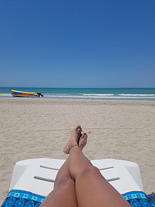 woman laying on white plastic sunbathing chair at the beach during daytime thumbnail