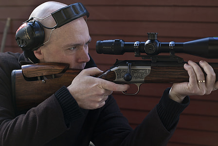 man sighting in scope while holding rifle thumbnail