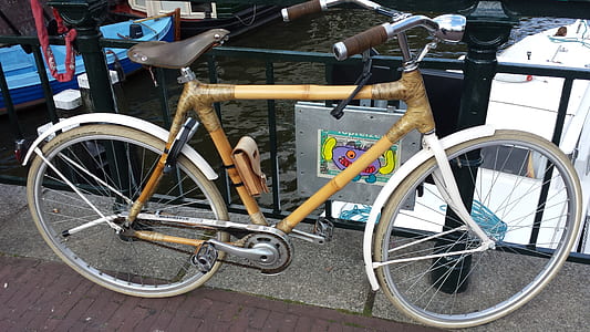brown bicycle parked upright beside wrought iron fence thumbnail