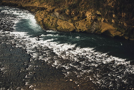 body of water beside cliff during daytime thumbnail