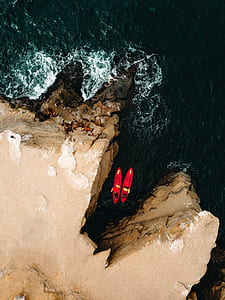 two person on red kayak in the middle of brown rocks thumbnail