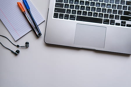 flat lay photography of MacBook beside two pens on top of ruled paper thumbnail