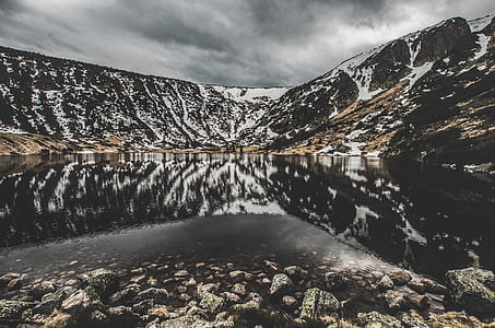 body of water at distance to partially snow covered rock formations thumbnail