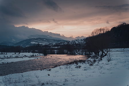 body of water beside snow during sunset thumbnail