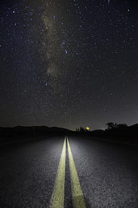 concrete road with yellow line in middle at nighttime photo thumbnail