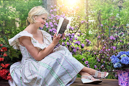 woman sitting while reading book outdoors thumbnail
