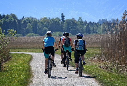 four people on biking on gray road near grass at daytime thumbnail