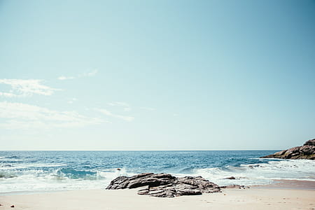 A rocky beach in sunlight with horizon in the background thumbnail