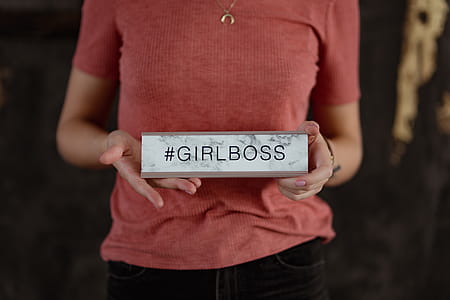 A young woman is holding a Girlboss Desk Sign thumbnail