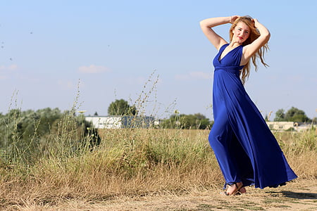 woman in blue dress posing beside green grass during daytime thumbnail