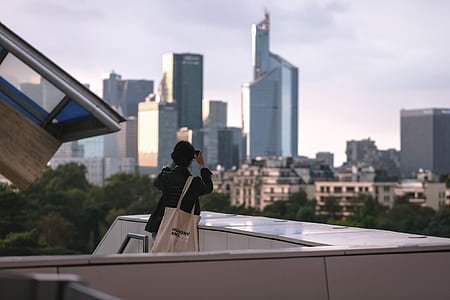 person taking picture of high-rise buildings at daytime thumbnail