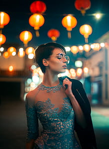 tilt shift lens photography of woman wearing illusion dress holding black jacket during night thumbnail