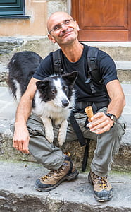 man in black crew-neck t-shirt siting on concrete stair beside adult border collie thumbnail