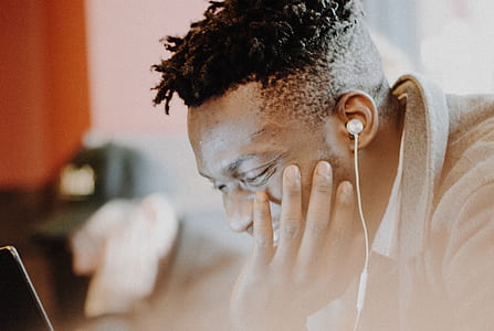 man wearing gray coat and white earbuds using laptop thumbnail