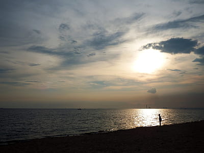 Man silhouetted in sunset sky on a beach next to the ocean thumbnail