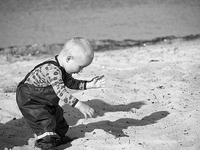 Grayscale Photography Of Toddler On Beach Sand thumbnail