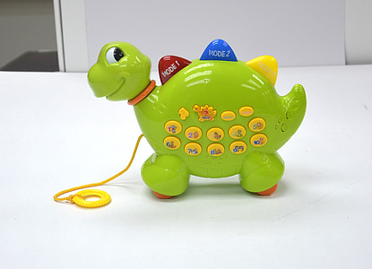 green and yellow dinosaur musical toy on white surface thumbnail