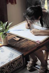 woman drawing on board on brown wooden table thumbnail