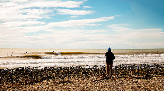 person standing on seashore under blue sky thumbnail