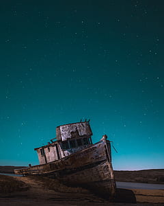 wrecked boat on seashore during nighttime thumbnail