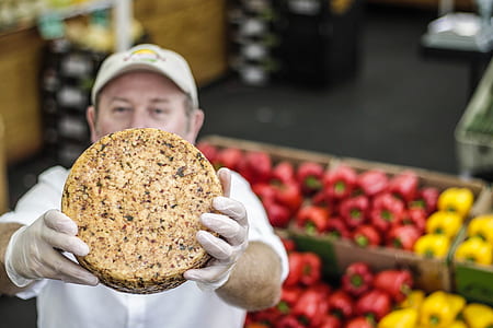 man showing round brown food near fruit stand thumbnail