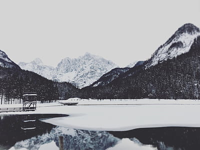 grayscale photo of mountain and snow cap field with reflection on body of water thumbnail