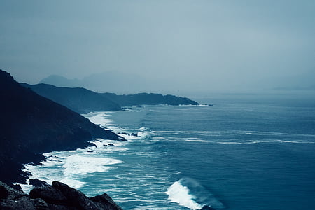 aerial photography of blue body of water near mountains under blue sky at daytime thumbnail