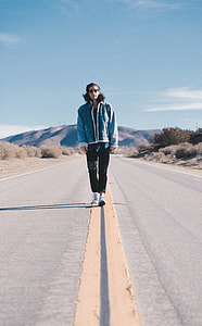 man standing on the middle of the road during day time thumbnail